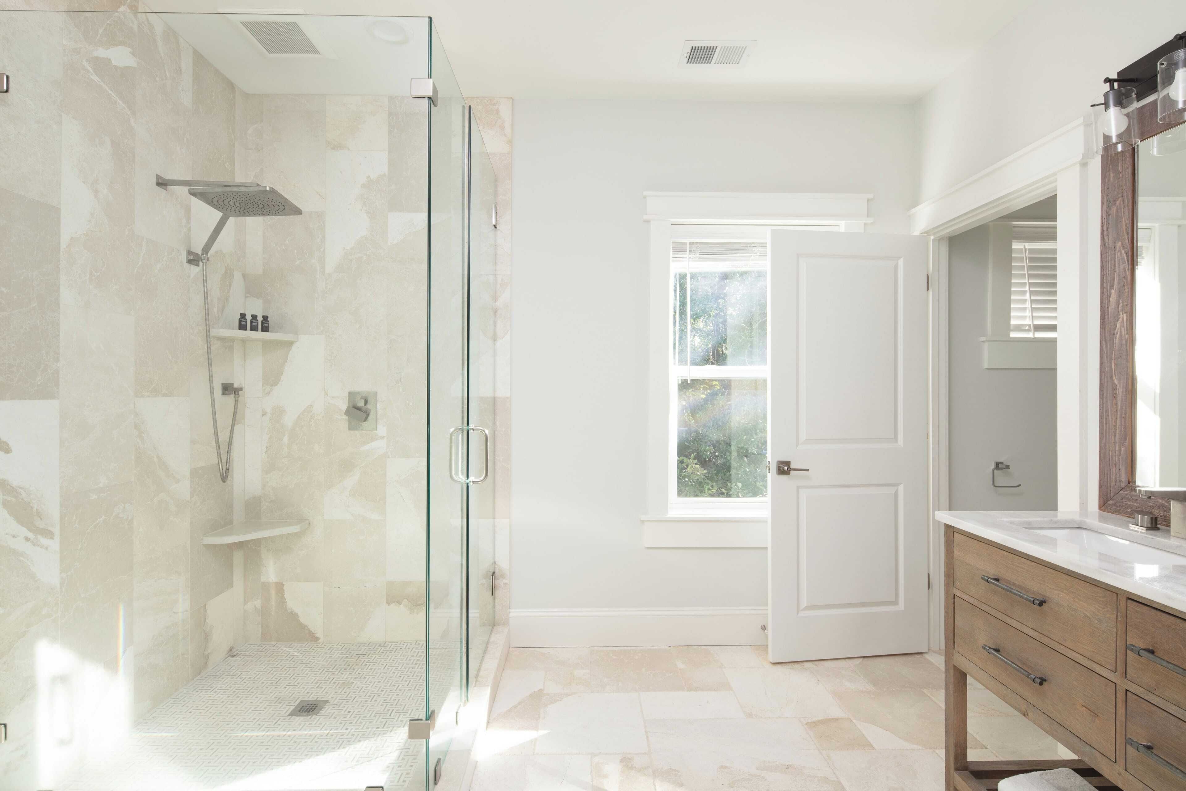 A modern bathroom with a glass-enclosed shower, a wooden vanity, and a large mirror.
