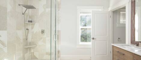 A modern bathroom with a glass-enclosed shower, a wooden vanity, and a large mirror.