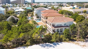 A coastal residential area with multiple two-story houses, a swimming pool, and a beach in the foreground. - Miramar Manor by Avantstay Walk to the Beach! (Miramar Beach)