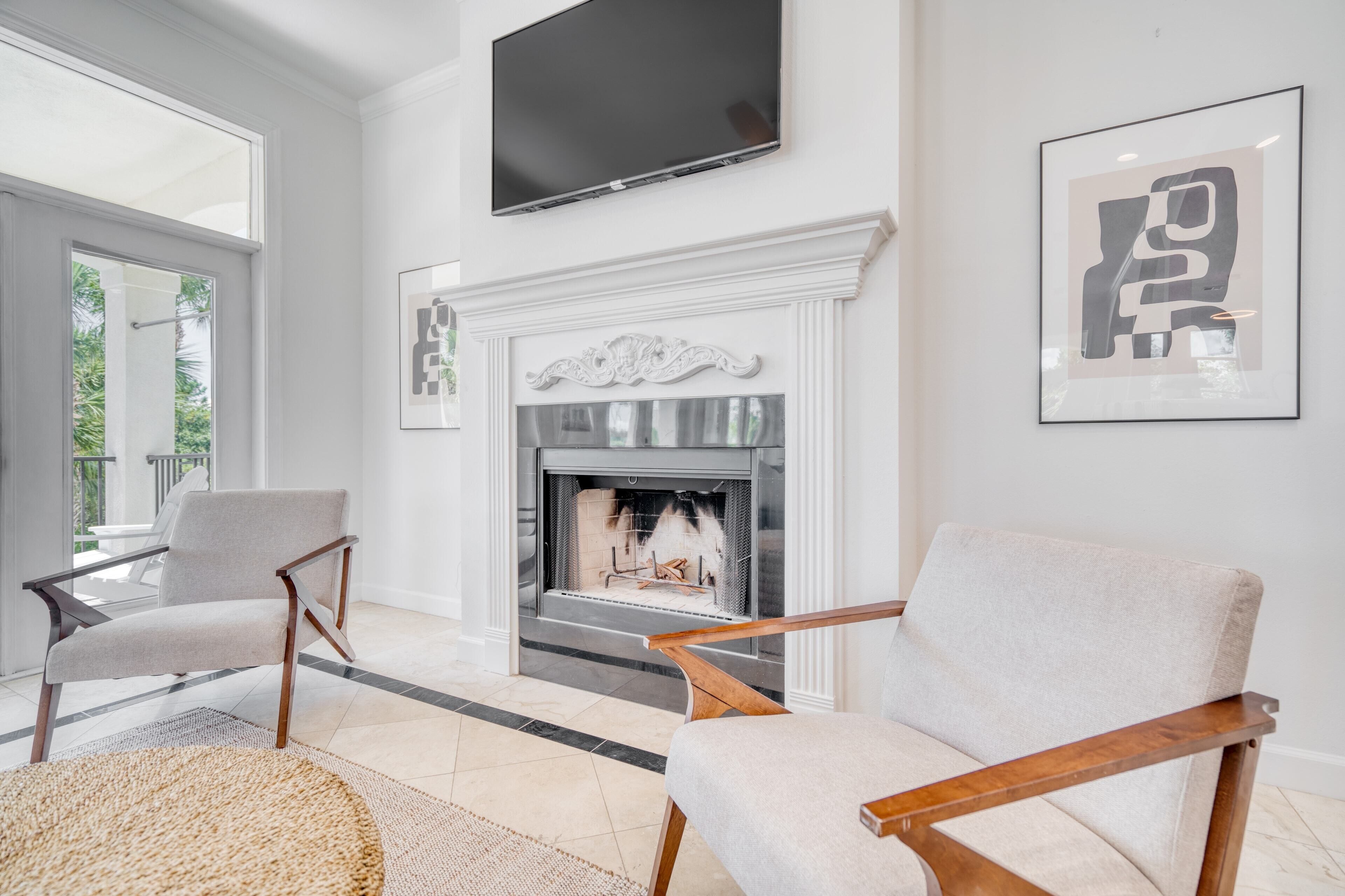 A modern living room with a fireplace, two armchairs, a television, and artwork on the walls.