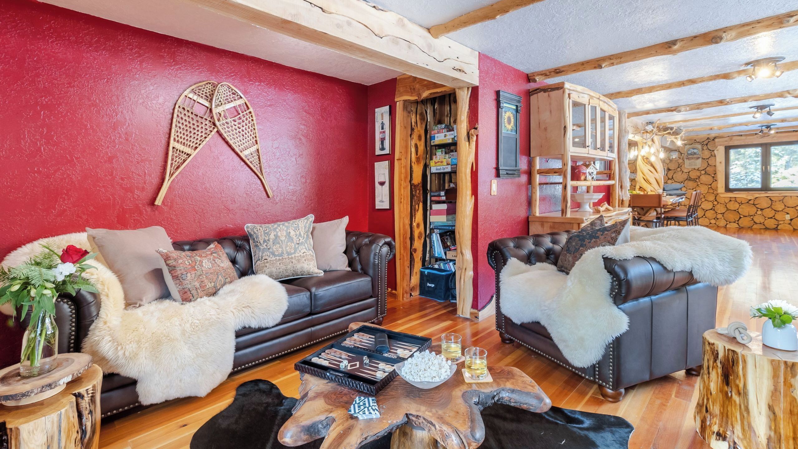 Een gezellige woonkamer met twee leren banken, een houten salontafel en een rode wand met een balkenplafond.