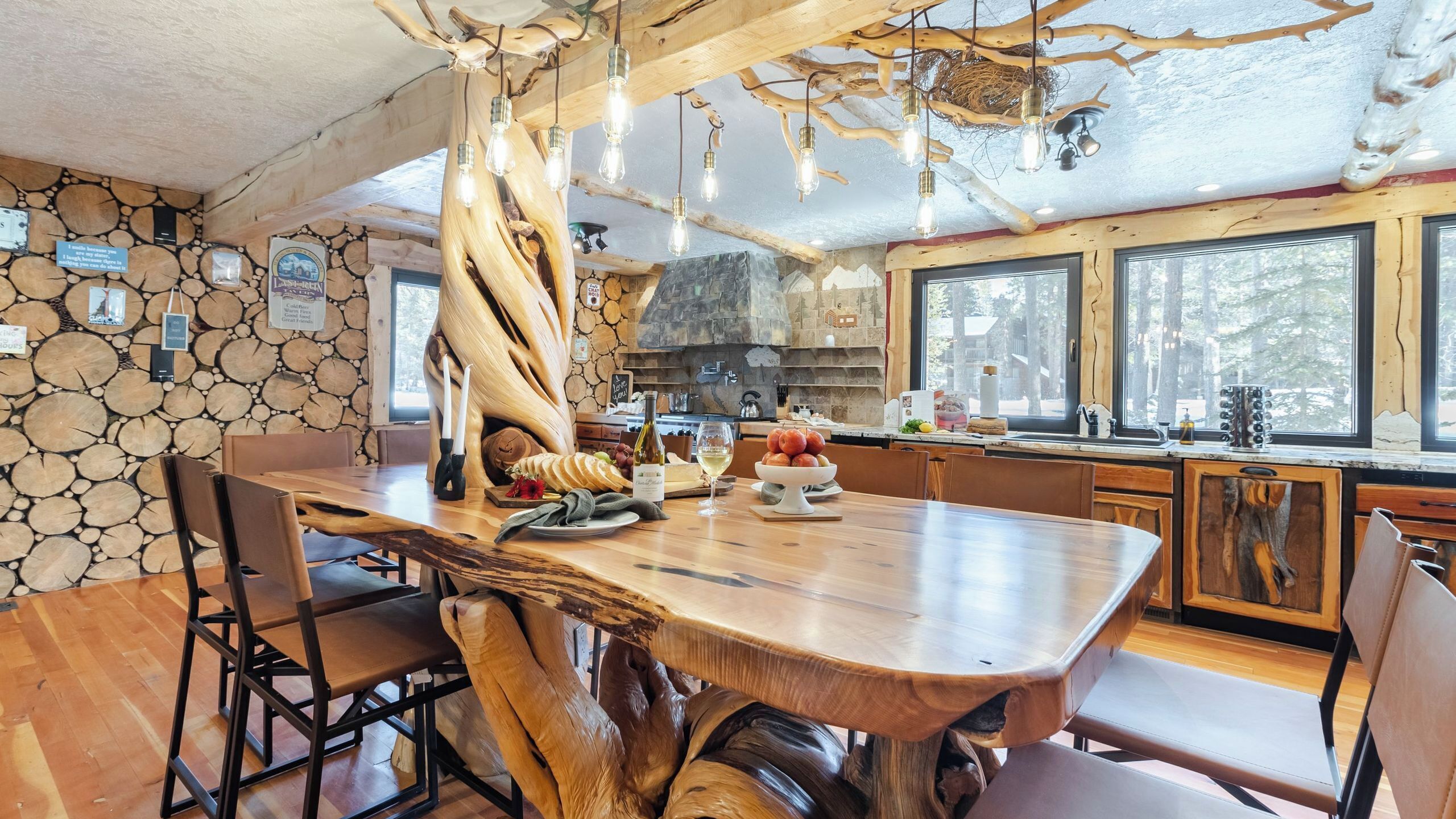 A rustic kitchen with a large wooden island, stone wall, and a stone fireplace.