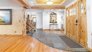 A wooden interior hallway with a stone-tiled floor, wooden doors, and a large mirror. - Base Camp by Avantstay Magical Cabin w/ Sauna, Hot Tub & Close to Snow & Golf (Bend)