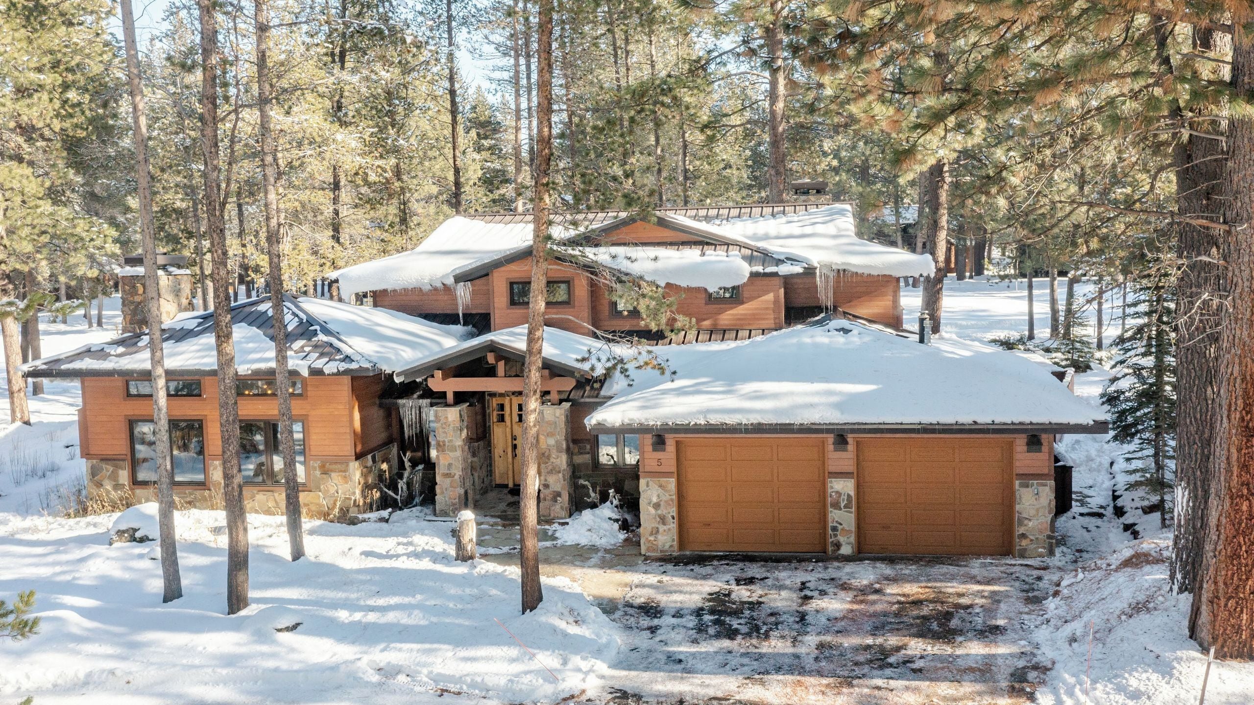 Un chalet doté de plusieurs cabanes en bois, entouré d’arbres couverts de neige.