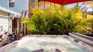 A hot tub in a backyard with a wooden fence, a bicycle, and a house in the background. - Oasis with Heated Pool (Siesta key)