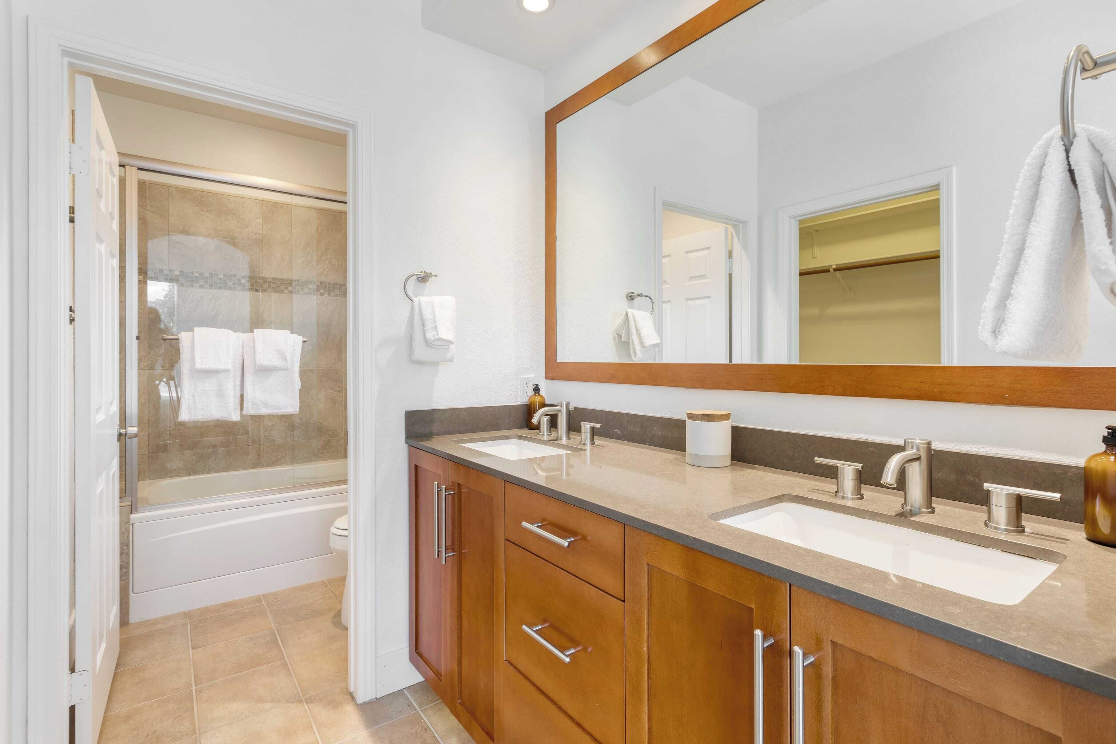 Un baño con cabina de ducha de vidrio, dos lavamanos, un espejo grande y muebles de madera.
