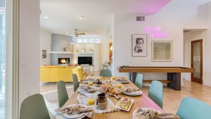 Espaço de refeições com mesa de bilhar, lareira e letreiro de neon.