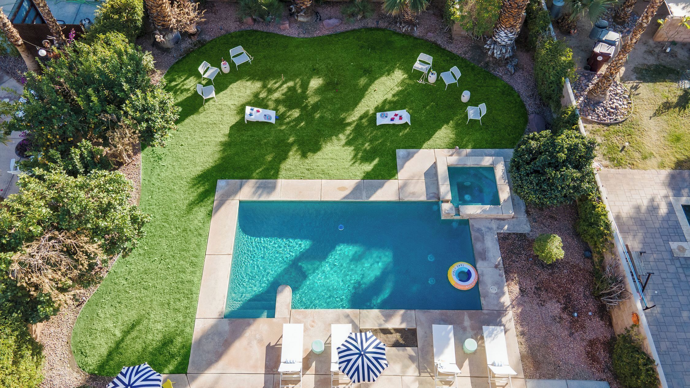 Vista aerea di un giardino con piscina, sedie a sdraio e una piccola area relax.