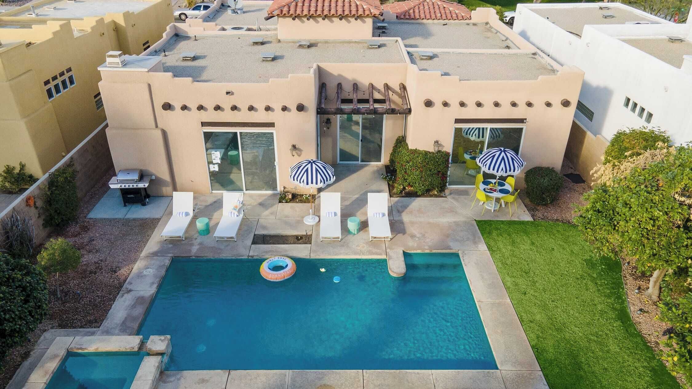 Una propiedad residencial con piscina, sillas de descanso y sombrillas.