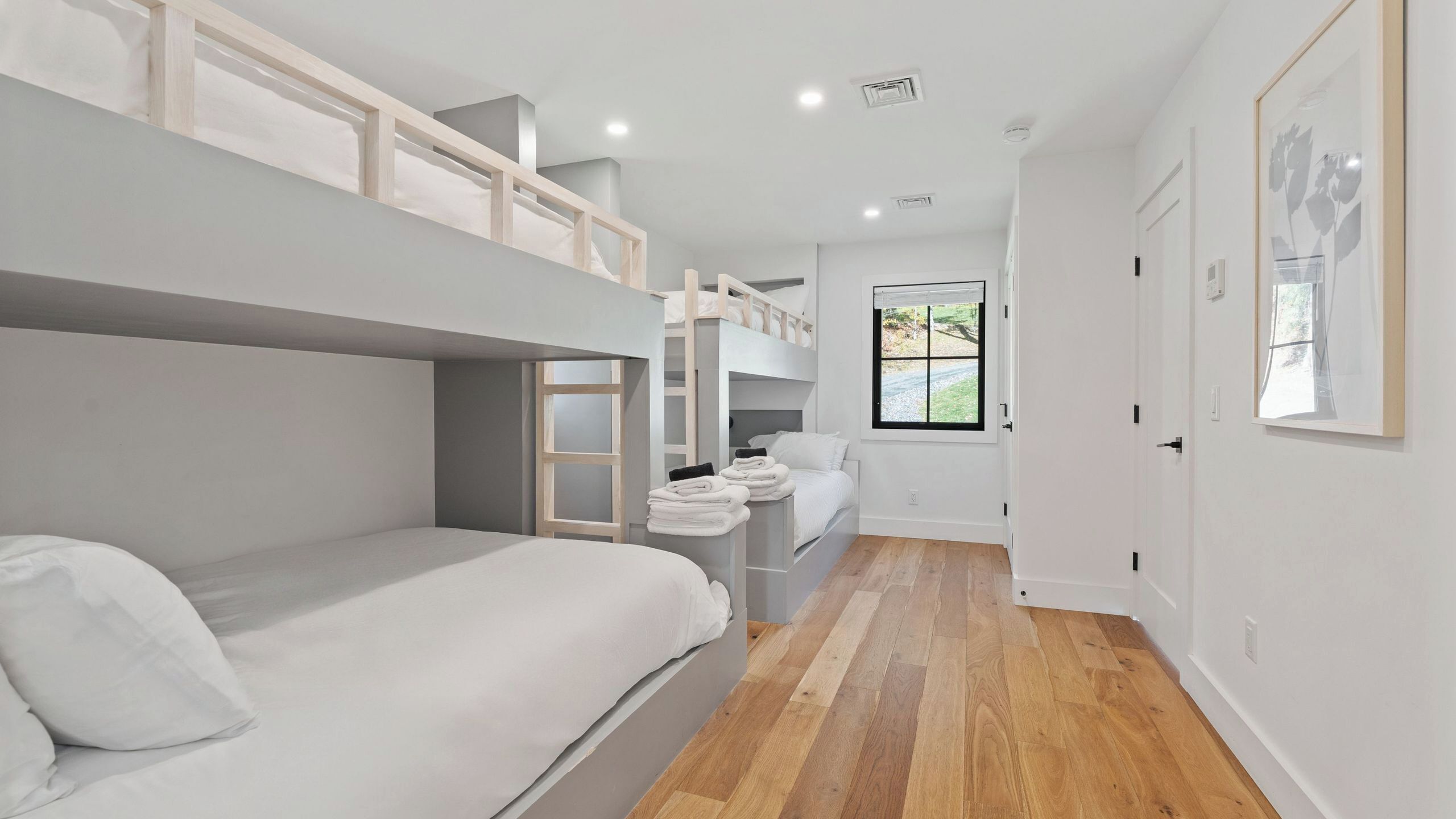 Une chambre avec des lits superposés, une fenêtre donnant sur un paysage agréable et une porte.