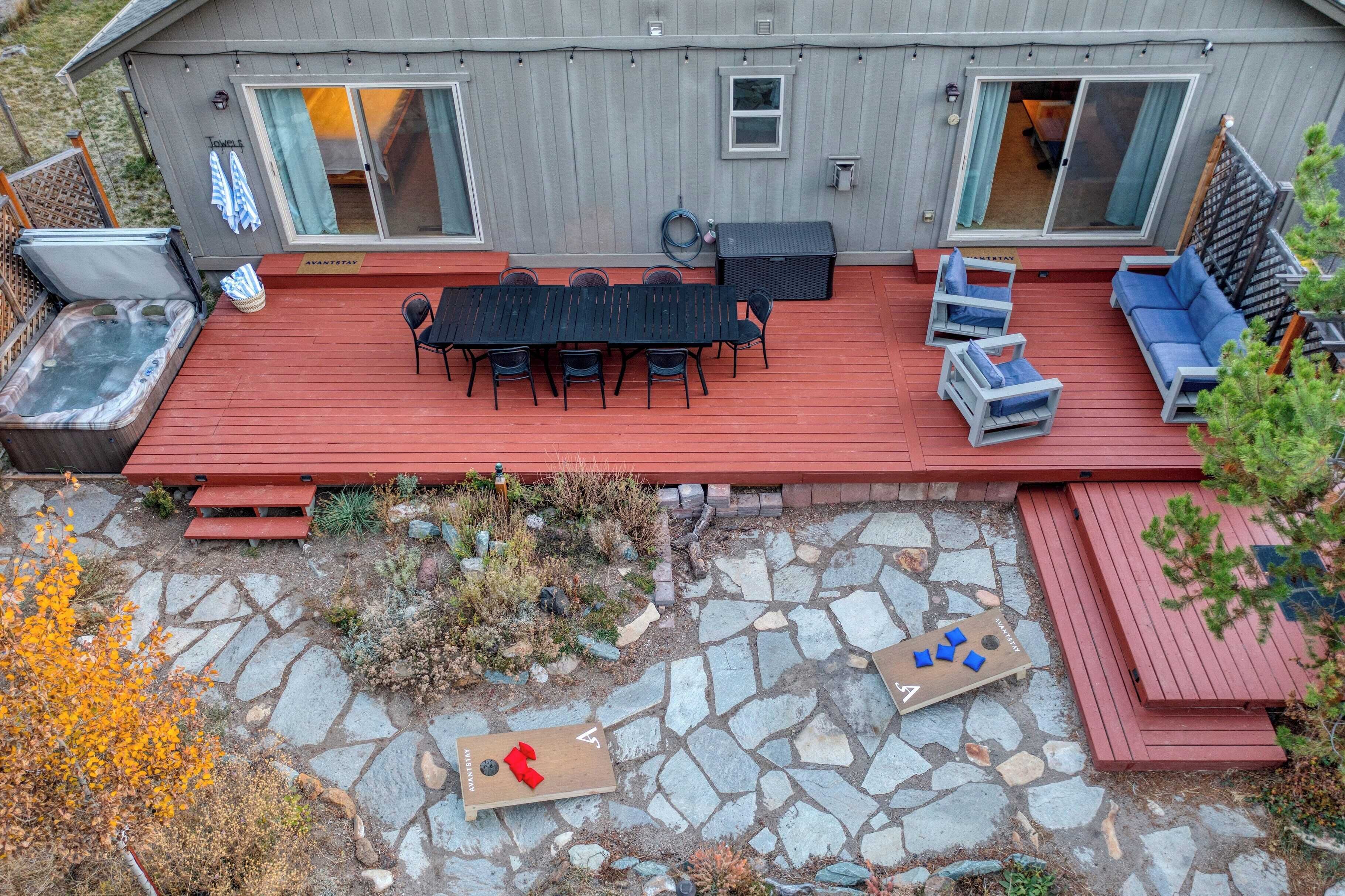 Eine überdachte Terrasse mit Steinpflasterung, Sitzgelegenheiten im Freien und einem Whirlpool.