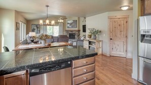 A spacious kitchen with a granite countertop, stainless steel appliances, and wooden cabinetry. - Hot Tub, Air Hockey, Foosball, Deck Lounge Near Sunriver & Mt. Bachelor Skiing (Bend)