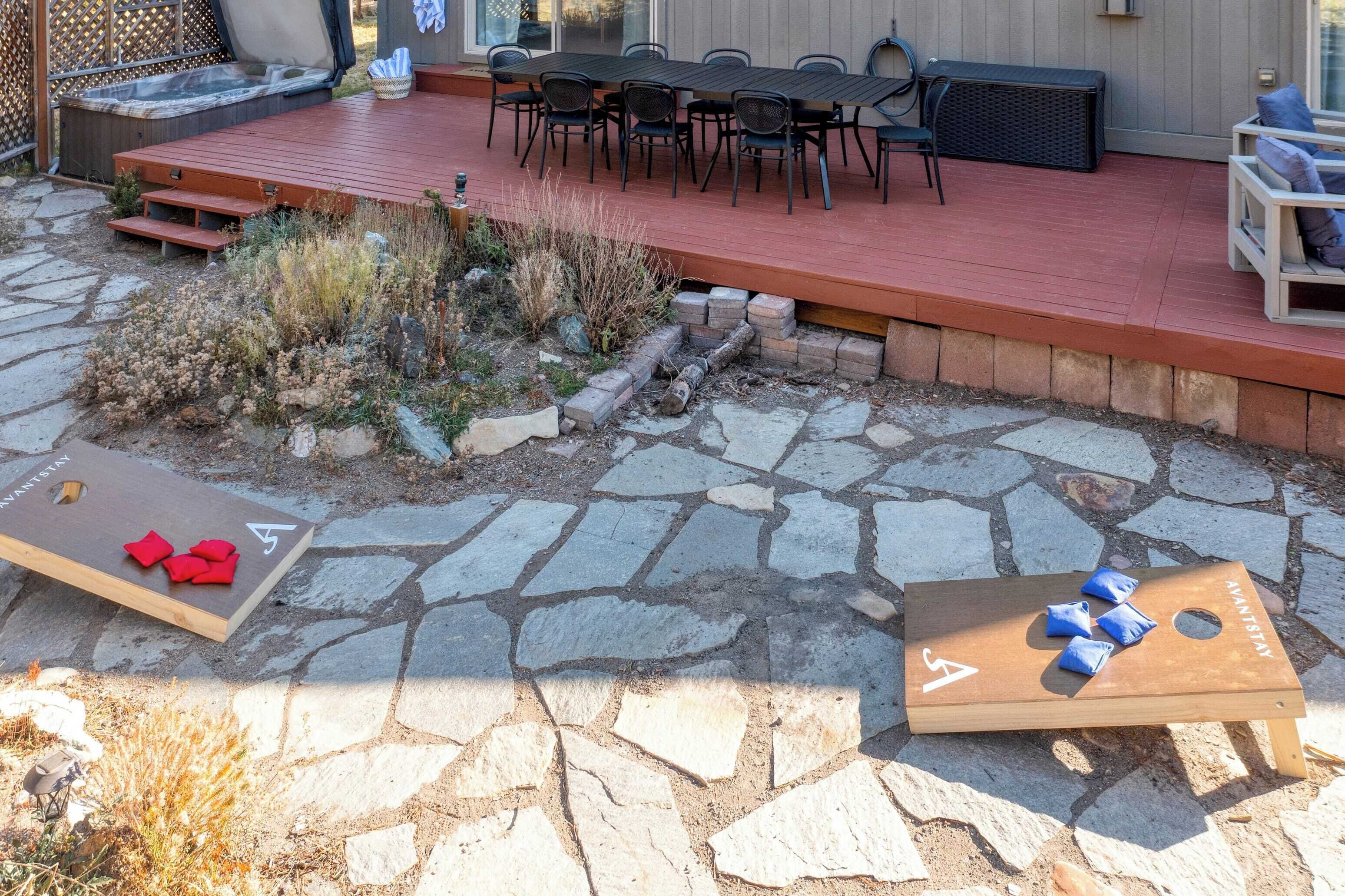 An outdoor deck with a stone patio, a hot tub, and a dining area with chairs and a table.