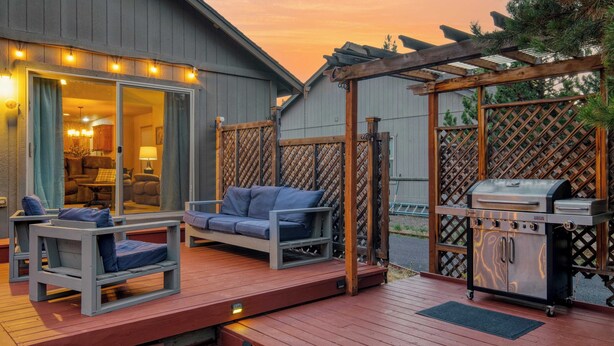 An outdoor deck with a barbecue grill, a sofa, and a dining table. - Hot Tub, Air Hockey, Foosball, Deck Lounge Near Sunriver & Mt. Bachelor Skiing (Bend)