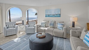 Ein Wohnzimmer mit Meerblick, ausgestattet mit einer Couch, Sesseln, einem Couchtisch und einer Lampe.