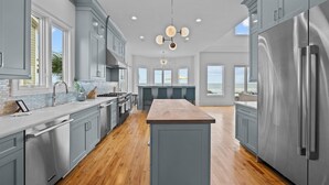 A modern kitchen with grey cabinets, stainless steel appliances, and a central island. - Luxury Oceanfront- Private Pool, Hot Tub, & Elevator! Can't beat location! (Isle Of Palms)