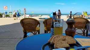 Une table avec une bouteille de Blanquette de Naumer, un verre et des tranches de pain, le tout posé sur une nappe bleue.