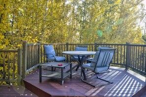 An outdoor patio with a table and chairs, surrounded by a wooden deck and a railing. - Luxury Hideaway/Stunning Vista View and Aurora (Fairbanks)