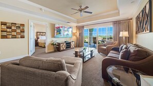 A spacious living room with a large flat-screen TV, comfortable seating, and a view to the outdoors. - Centre Court Sunbeam: Free Water Park, Golf View, Pool, Near Disney (Kissimmee)
