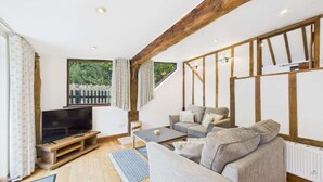A modern living room with a TV, sofas, and a staircase. - The Cote, Little Upton Farm (Ashey)