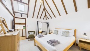 A bedroom with a bed, wooden headboard, bedside tables, a desk, a chair, and a mirror. - The Cote, Little Upton Farm (Ashey)