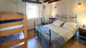 A bedroom with a metal bed frame, a wooden bunk bed, a small bedside table with a lamp, and a window with a view of the outside. - 2 bedroom nice home in Bidarray (Bidarray)