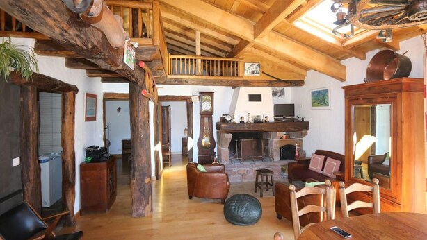A rustic interior with a wooden dining table, chairs, a fireplace, and a loft area with a wooden staircase. - 2 bedroom nice home in Bidarray (Bidarray)