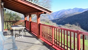 A covered outdoor seating area with a table and chairs, overlooking a mountainous landscape. - 2 bedroom nice home in Bidarray (Bidarray)