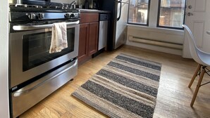 Een keuken met houten kastjes, roestvrijstalen apparatuur, een fornuis en een koelkast.