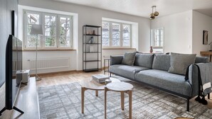 Een moderne woonkamer met een grijze bank, een salontafel en een boekenkast.