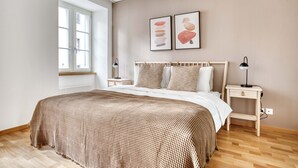 Een slaapkamer met een groot bed, twee nachtkastjes, een raam en kunst aan de muur.