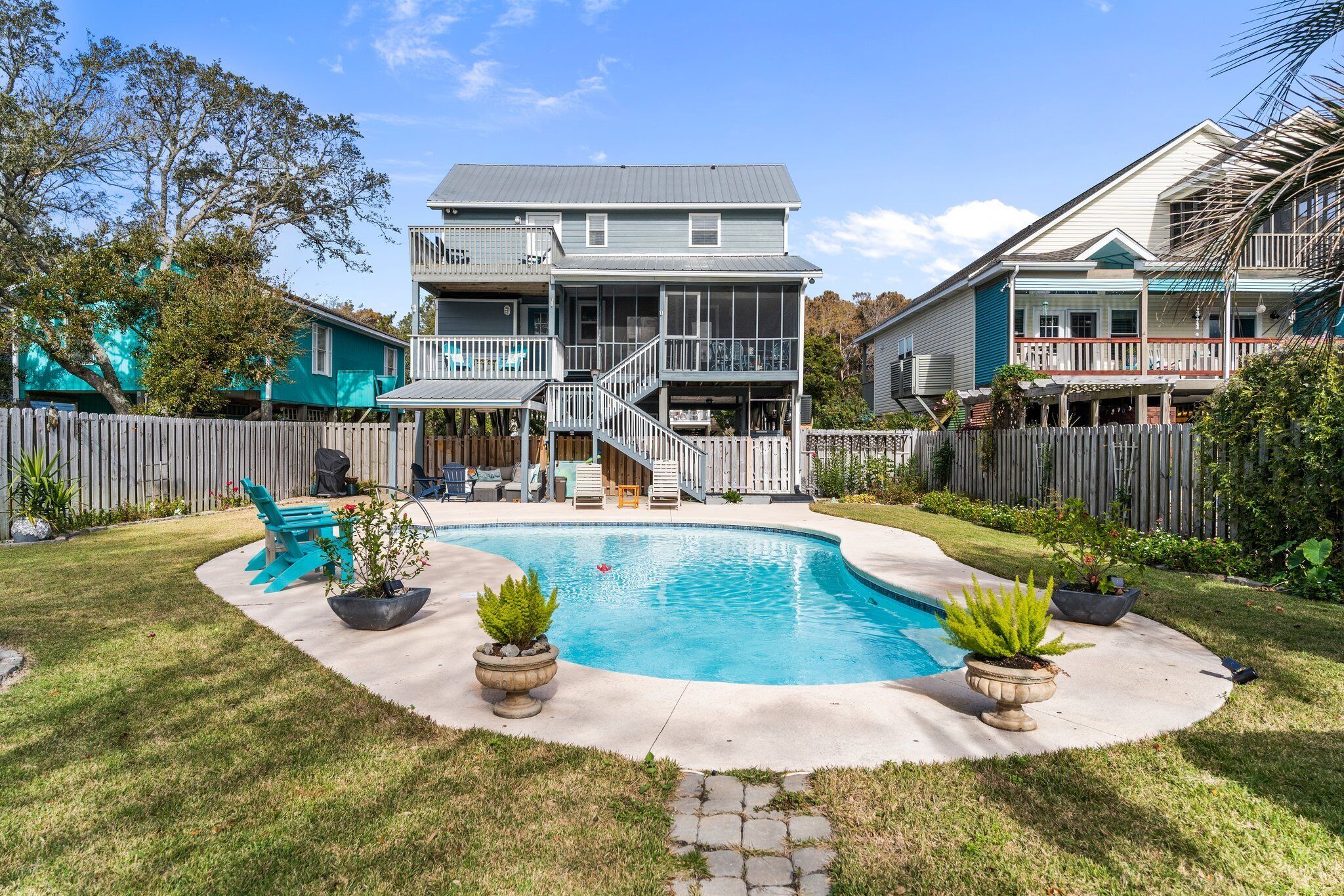 Uma casa de dois andares com piscina, um deck coberto e um quintal cercado.
