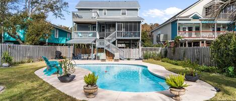 Uma casa de dois andares com piscina, um deck coberto e um quintal cercado.