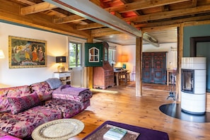 A cozy living room with a wooden ceiling, a sofa, a fireplace, and a traditional cabinet.