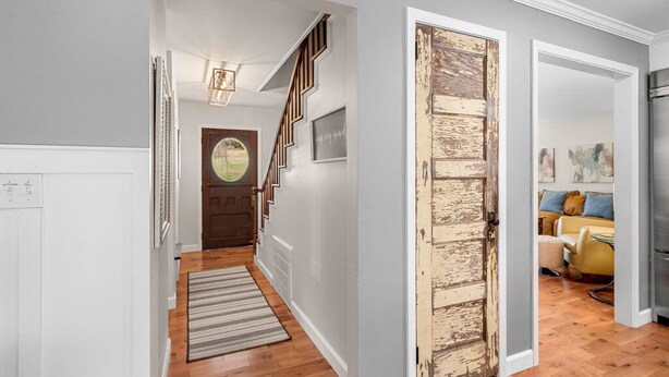 Un couloir doté d’un plancher en bois, d’un escalier et d’une porte dont le bois a un aspect vieilli.