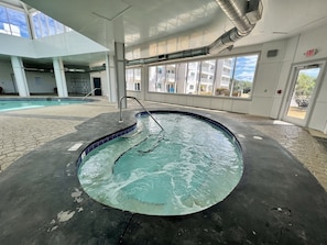 A swimming pool with a tiled edge, a metal ladder, and a view of buildings outside.