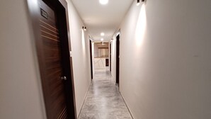 Un pasillo con suelo de mármol, puertas de madera e iluminación empotrada.