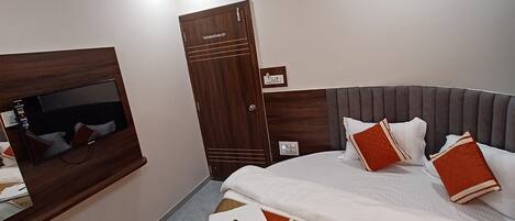 A hotel room with a bed, a television, a wardrobe, and a ceiling fan.