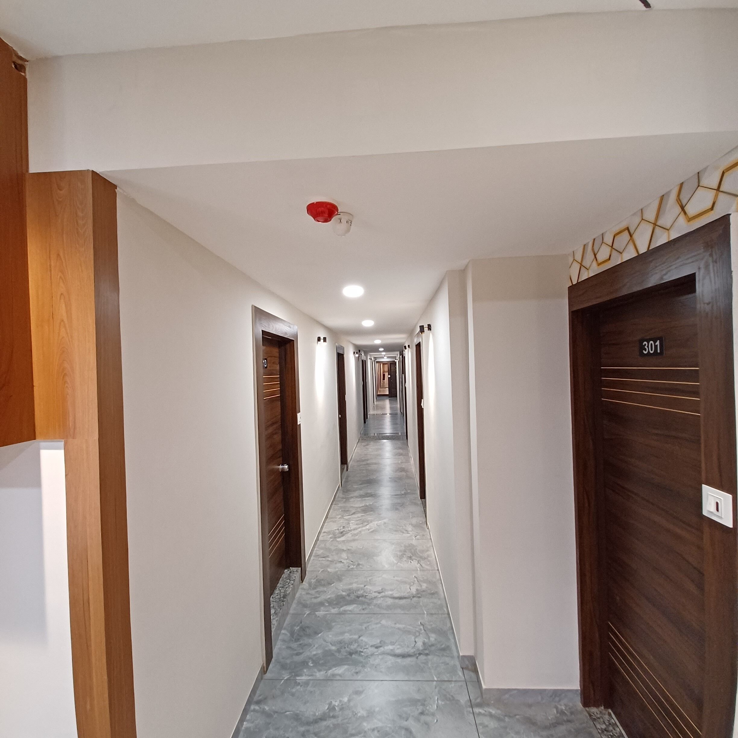 A hallway with wooden doors and a marble floor, leading to a room marked with the number 301.