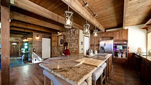 Une cuisine spacieuse avec des poutres en bois, des plans de travail en granit et des appareils électroménagers modernes.