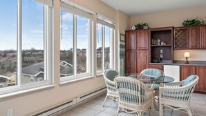 A spacious kitchen with large windows, wicker chairs, and a dining table. - Family Getaway • Show & Golf Discounts • Resort Amenities (Branson)