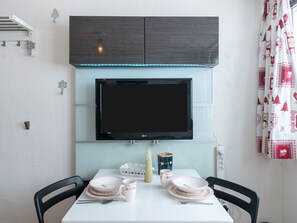 Enjoy meals in this cozy dining area with a flat-screen TV, decorative light fixture, and festive table setting.