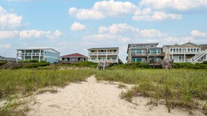 A beachfront property with multiple buildings, a sandy path leading to the beach, and a clear sky. - Hobbs Realty - Oceanfront Home w/Expansive Decks and Second Living Area w/Futon (Holden Beach)