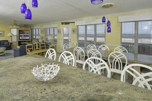A dining area with a granite table, white chairs, and blue hanging lights.