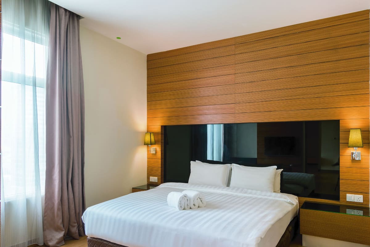 Ein Hotelzimmer mit einem großen Bett, einer Wandpaneelausstattung aus Holz, zwei Nachttischlampen und einem großen Spiegel über dem Bett.