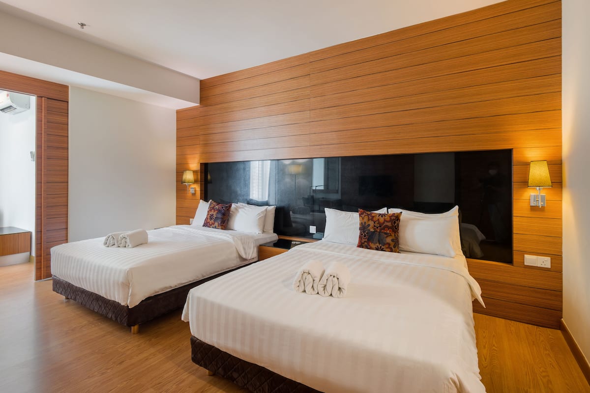 Ein Hotelzimmer mit zwei Betten, Holz-Kopfteilen und Nachttischlampen.