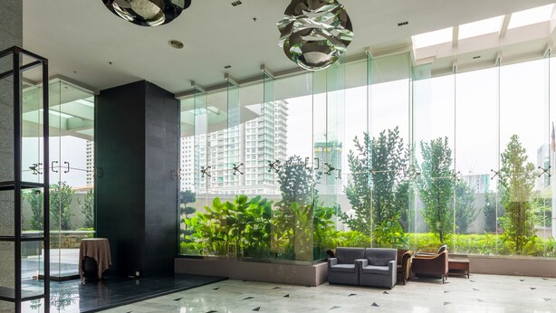A modern lobby with a glass wall, a sofa, a chair, and a small table. - Dua Sentral Kuala Lumpur, Roam (Kuala Lumpur)