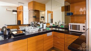 A modern kitchen with wooden cabinetry, a black countertop, and a microwave. - Dua Sentral Kuala Lumpur, Roam (Kuala Lumpur)