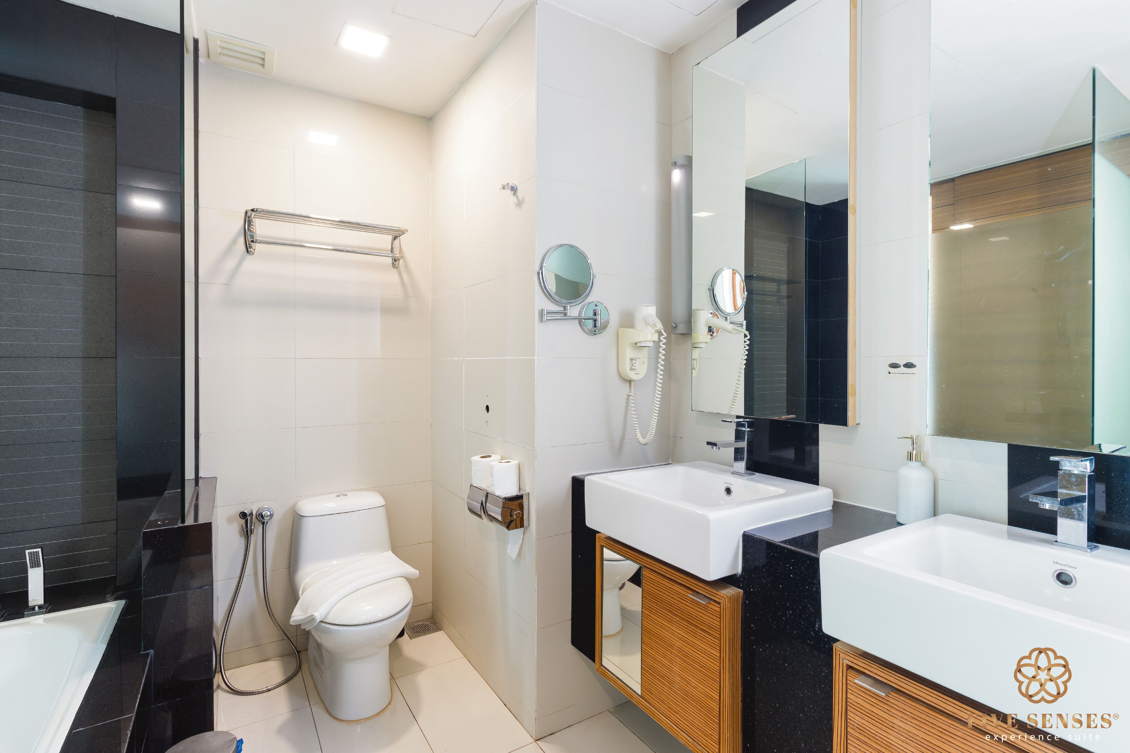 Une salle de bain moderne avec des toilettes blanches, un lavabo et un grand miroir.
