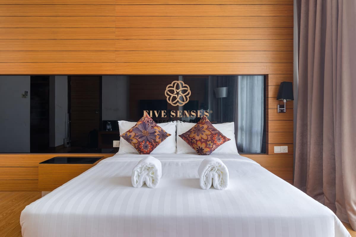 Ein Hotelzimmer mit einem großen Bett, zwei Zierkissen, einem Kopfteil mit einem Logo und einem Nachttisch.